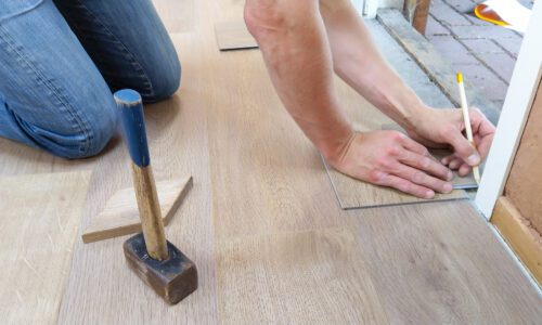Man holding pencil to mark out vinyl flooring tiles.