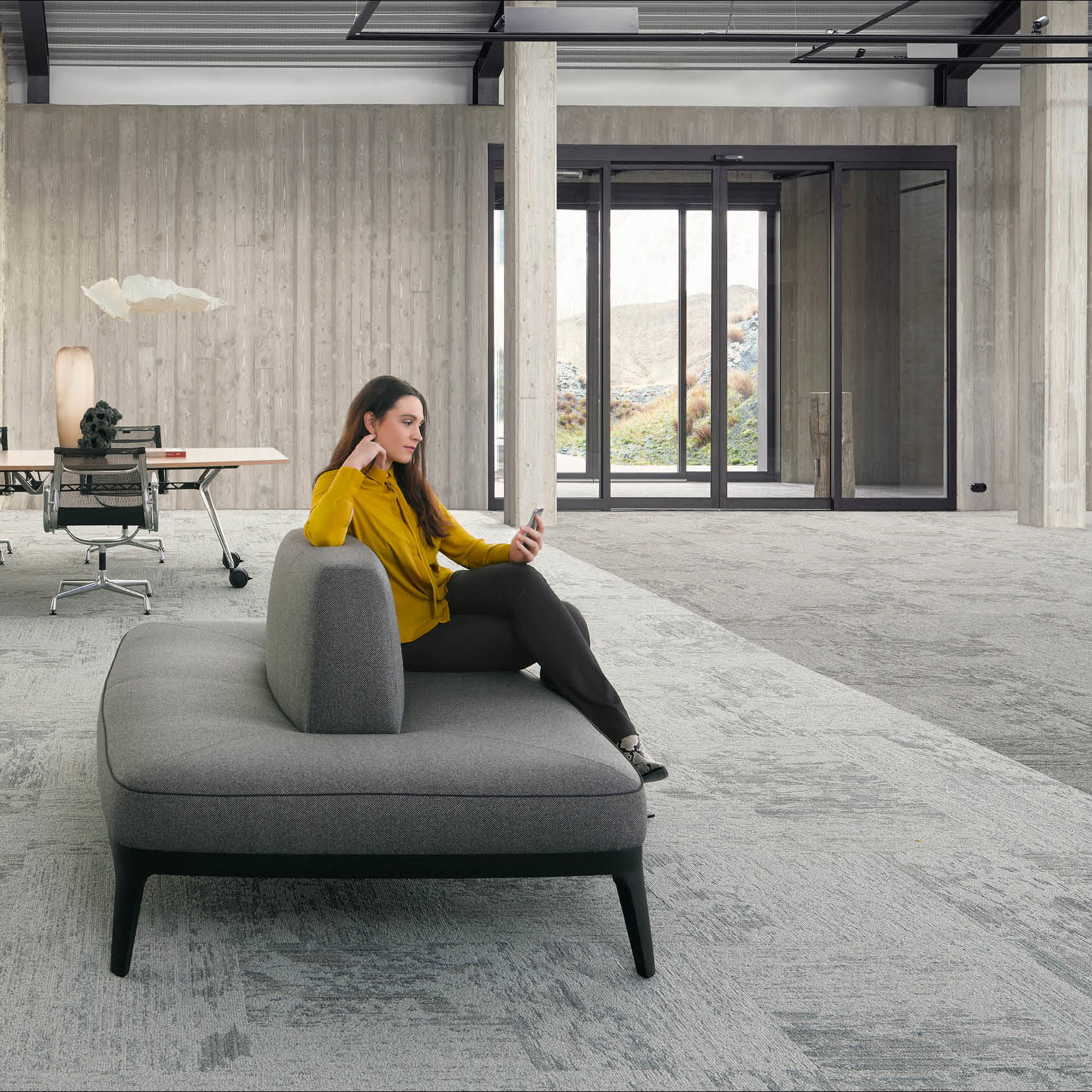 Desso Breccia Carpet Tile in a large commercial open space with sofa and woman on her phone